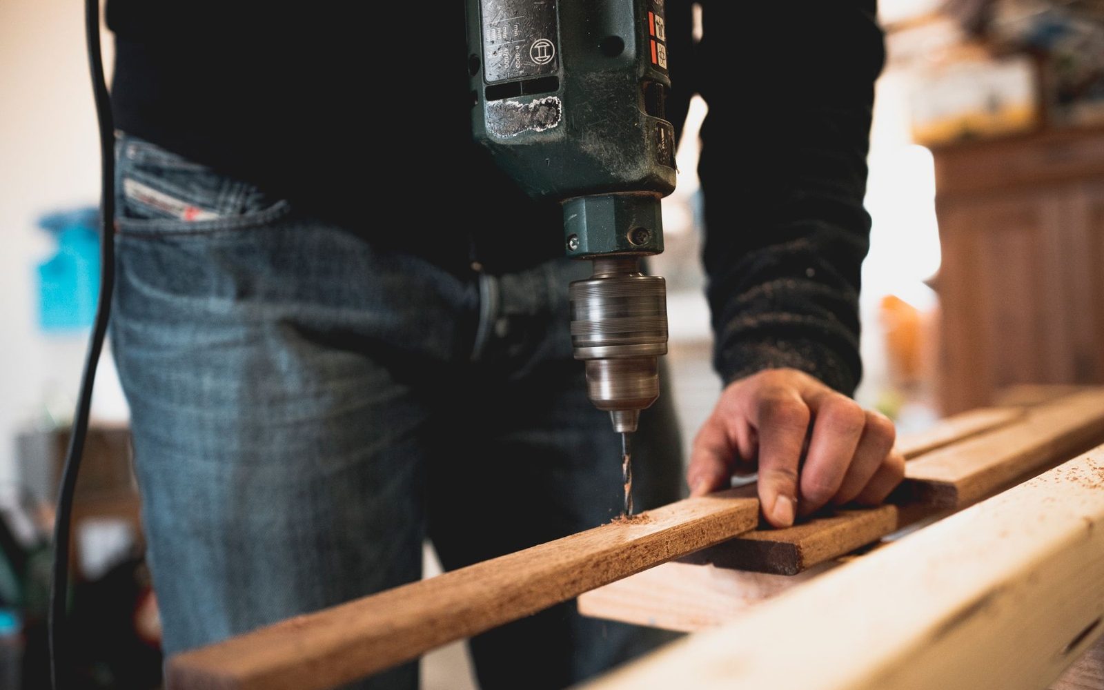 Hands using a cordless drill on a length of timber